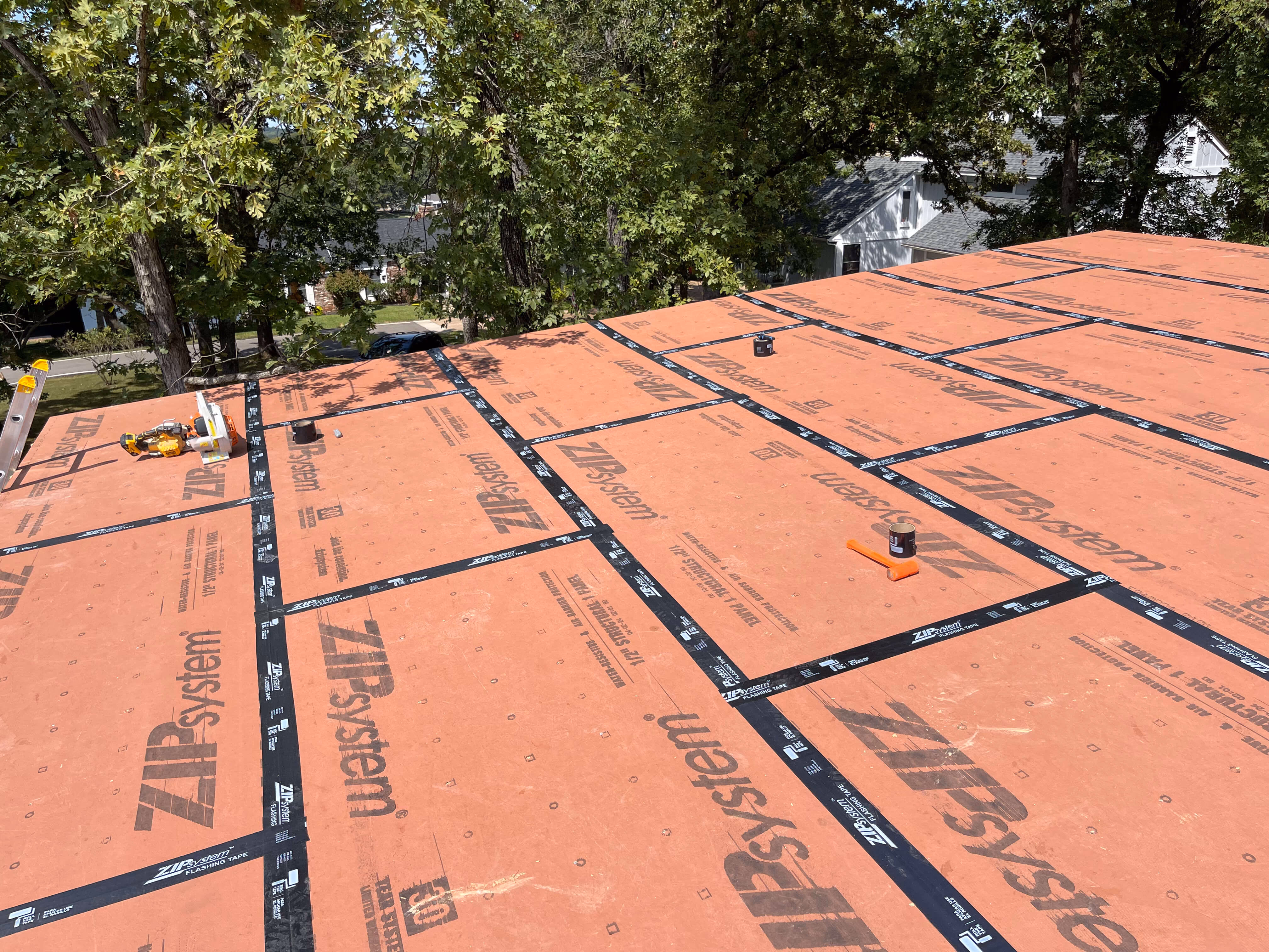 Roof under construction with ZIP System panels and black flashing tape on a sunny day.